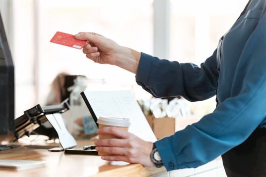 Mulher em uma cafeteria, pagando um café com o cartão de crédito